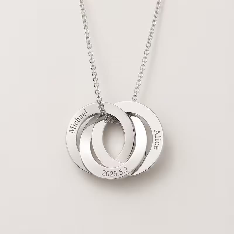 A silver chain necklace with three interlocking circular pendant rings engraved with the names Michael, Alice, and the date 2025.5.