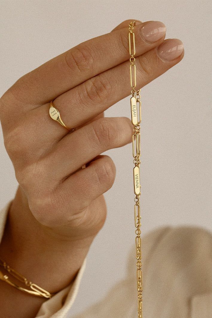 Gold bracelet being held by a hand against a neutral background